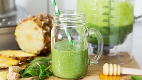Vihreistä vihanneksista vasta valmistettua smoothie-juomaa lasikannussa, jossa on pilli