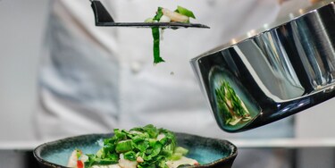 Infinite Chef -kattilasta ruokaa asetteleva kokki