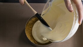 Leipuri, joka kaataa tasaisen juustokakkuseoksen kakkuvuokaan kypsennystä varten