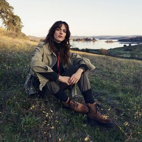 Nainen istuu niityllä