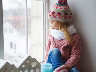 Tyttö istuu ikkunassa talvisen päivänä