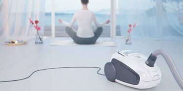 Joogaa harrastava nainen, etualalla Electrolux Ultra Silencer -pölynimuri