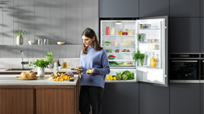 Woman in kitchen with open fridge in background
