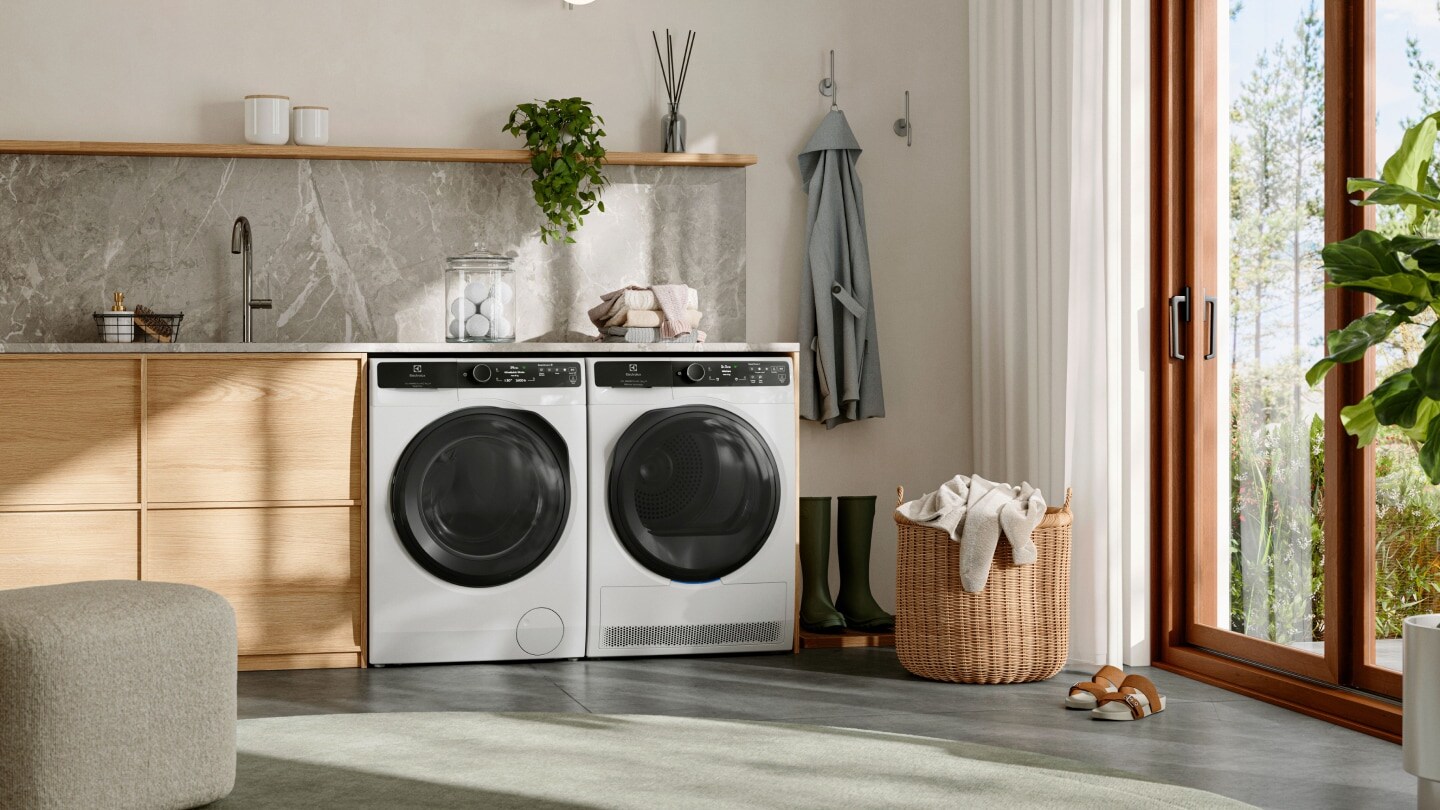 Electroluxin pesukone ja kuivausrumpu vierekkäin valoisassa kodinhoitohuoneessa. 