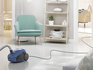 Imuri keskellä huonetta pitkän johtonsa kanssa