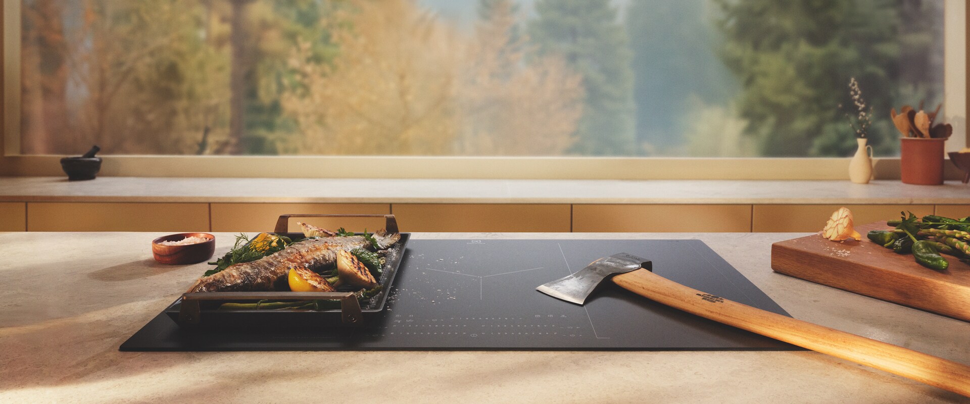 An axe is placed on an induction hob with SaphirMatt surface next to grilled food.