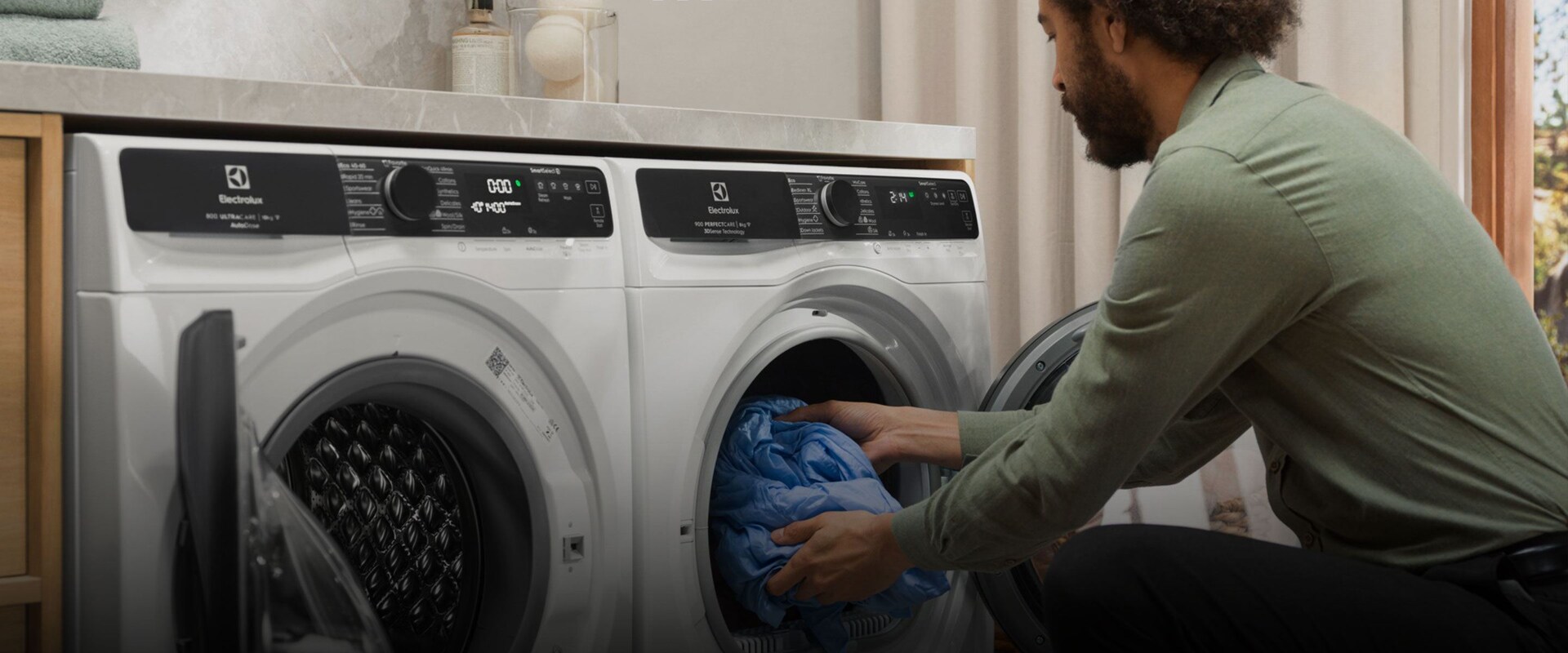 Mies tyhjentää pyykkejä pesukoneesta.