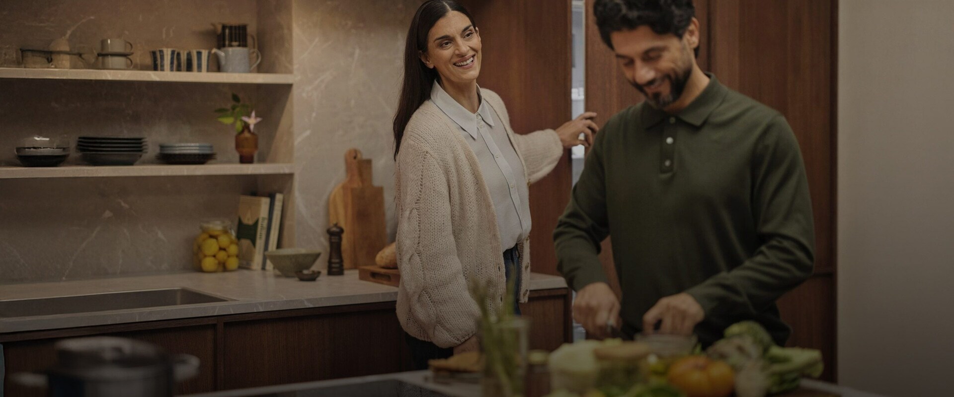 Pari valmistaa ruokaa modernissa keittiössä, jossa on integroidut jääkaappi ja pakastin.