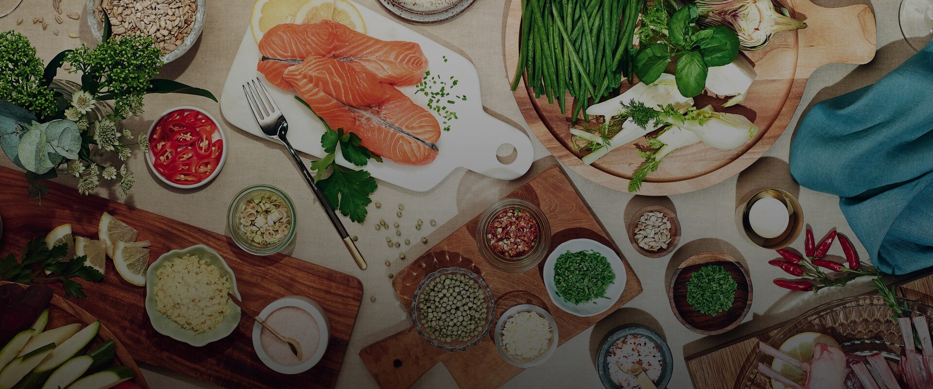 Raaka-aineita, kuten lohta ja yrttejä leikkuulaudoilla.