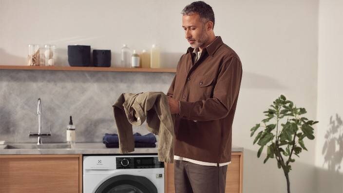 Mies pesee pyykkiä Electroluxin pesukoneella. 