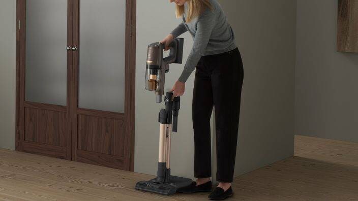 Nainen on ottamassa käyttöön varsi-imuria. 