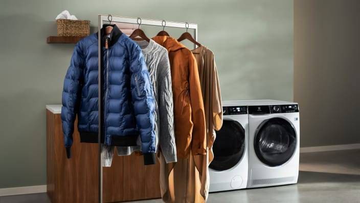 Pestyjä vaatteita kuivumassa tangolla Electroluxin pesukoneen ja kuivausrummun edessä.